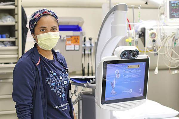 Danielle Acosta, Emergency Department RN, stands with the remote assistance robotic technology