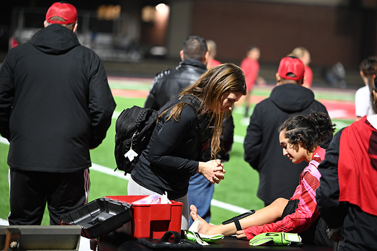 Jessica Johnson, ATC, attending to injured student on field